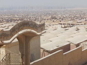 The sign reads: Cemeteries of St. Michael, 6 October City. The vast gray expanse behind are the Muslim graves.