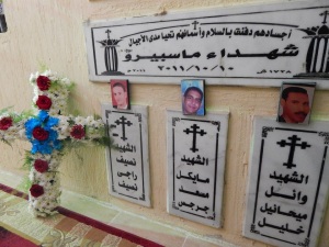The plaque reads: The Martyrs of Maspero, with a date of October 10, 2011. One relative explained it is the 10th because that is when the autopsies were finalized, though the massacre took place on the 9th. The phrase above says: Their bodies are buried in peace, and their names live throughout the generations.